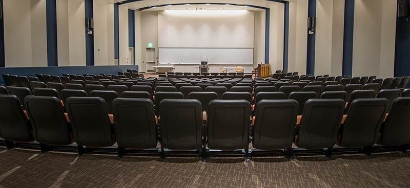 Leerer Hörsaal mit gestuften Sitzreihen und klarer Sicht zur Bühne