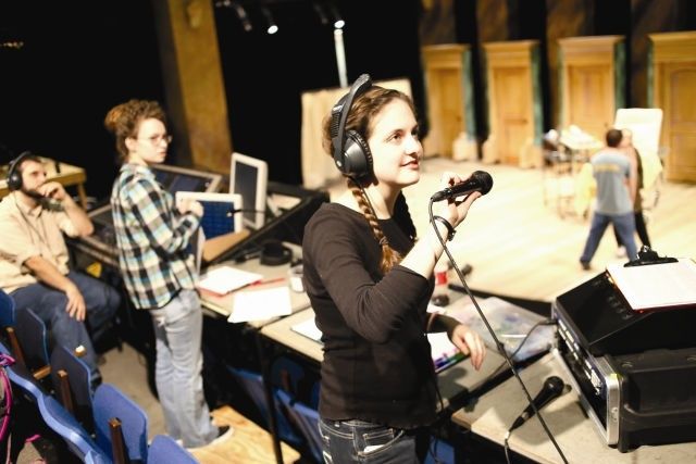Bühnenmitarbeiterin mit Kopfhörern und Mikrofon bei einer Theaterprobe